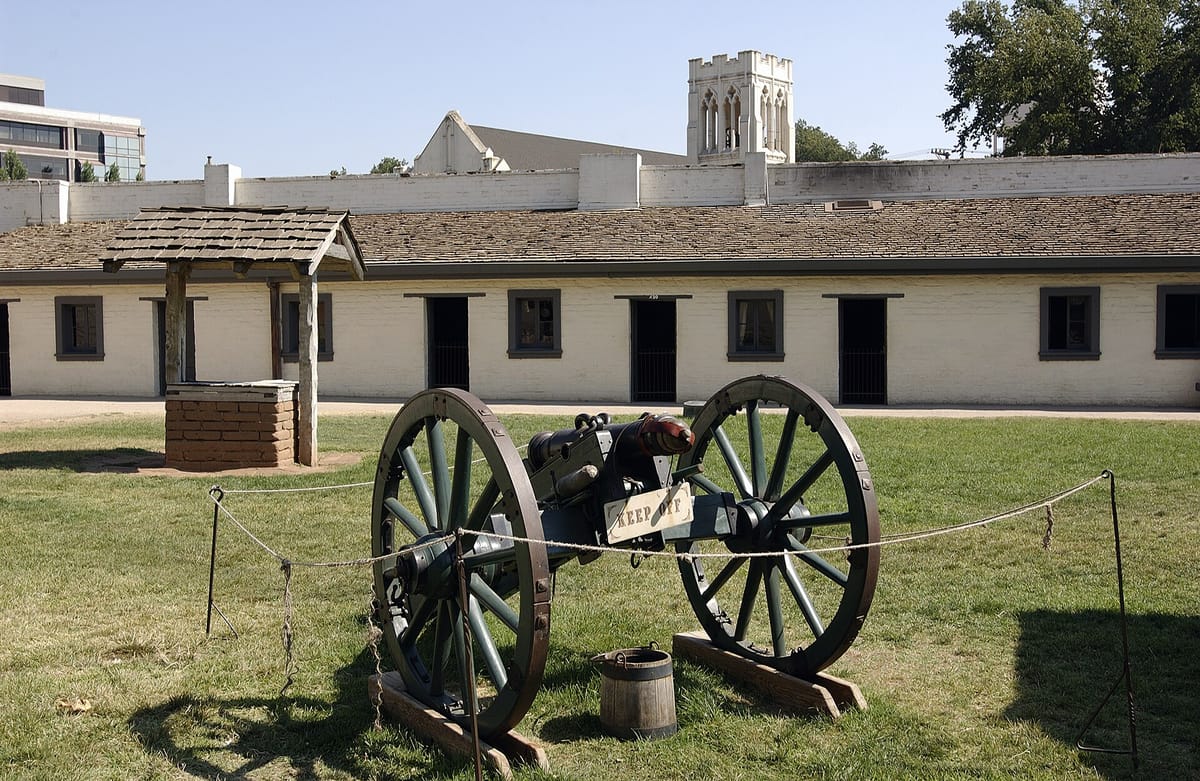 An adobe building and a cannon inside Sutter's Fort