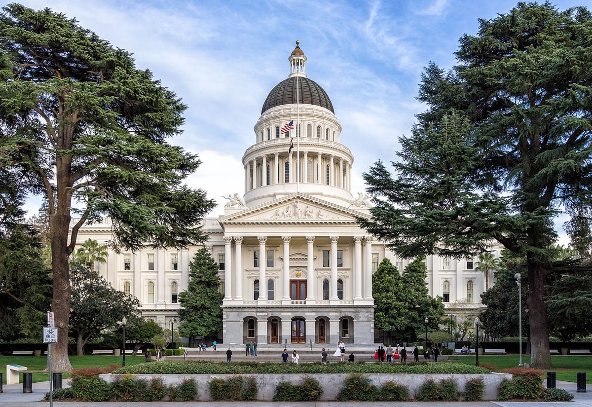 The California State Capitol and its dome behind tall trees